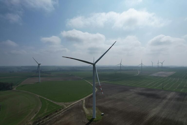 A breathtaking aerial view of wind turbines amidst vast green fields, showcasing renewable energy potential.